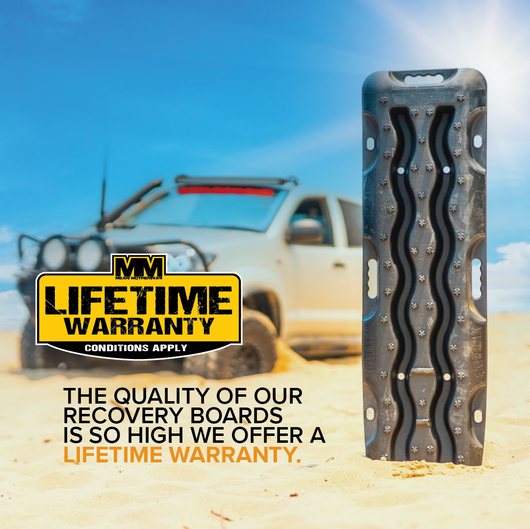 A gray 4x4 vehicle is stuck in sandy terrain. In the foreground, there is a pair of black Exitrax Recovery Board 1110 Series used for off-road recovery. Text on the image reads, "Lifetime Warranty Conditions Apply - The quality of our Exitrax Recovery Boards is so high we offer a lifetime warranty.