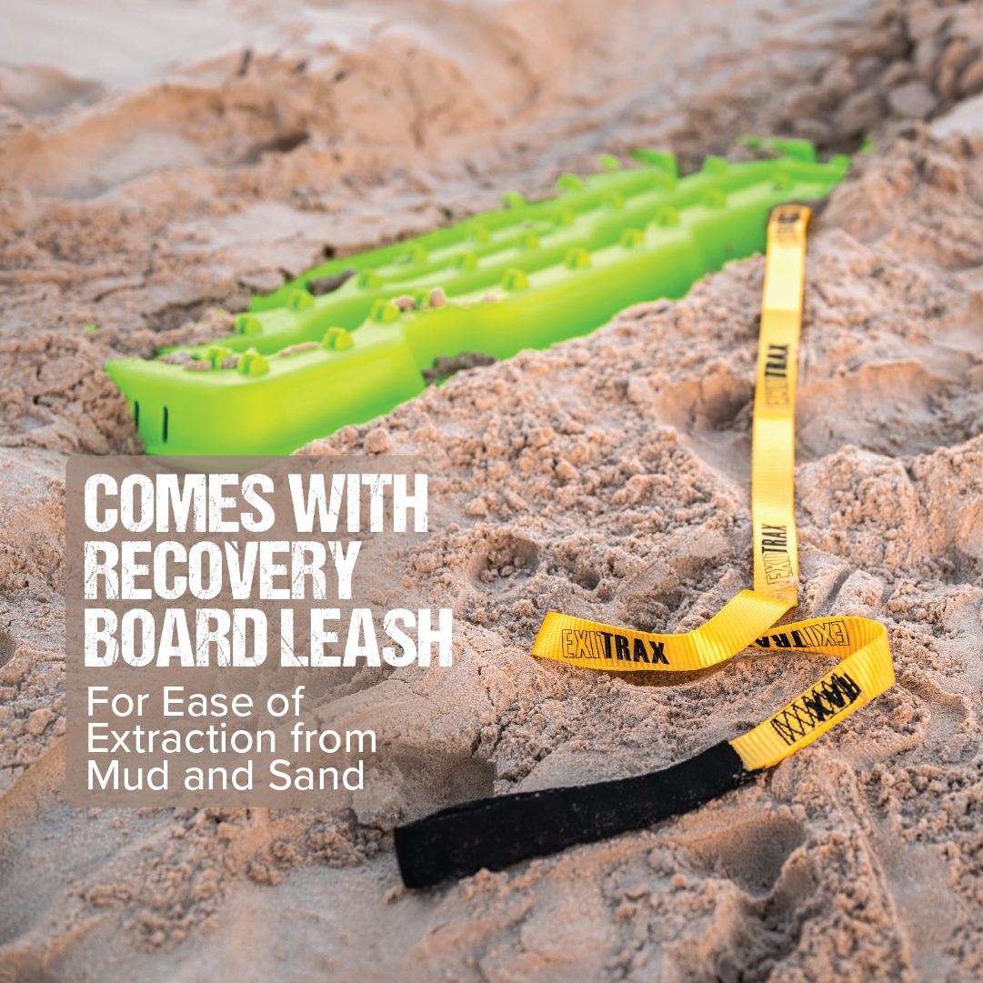 A black Exitrax Recovery Board 1110 Series - Pair, partially buried in sand with yellow and black straps attached. The text on the left reads "Comes with Recovery Board Leash" and "For Ease of Extraction from Mud and Sand." Designed by Exitrax for traction enhancement, this board ensures reliable performance every time. Exclusive for trade show only.