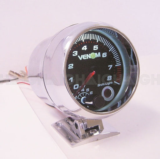 A close-up of the Mean Mother 4x4 Gauge Venom 3 3/4" Tacho with a black face and white numbers, chrome housing, mounted on a metal bracket, with wiring visible in the background.