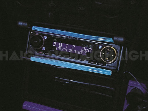 Close-up of the Mean Mother 4x4 Illuminated Line Blue car stereo system with a digital display showing 8:12 and settings. Controls glow with blue backlighting in a dark environment.