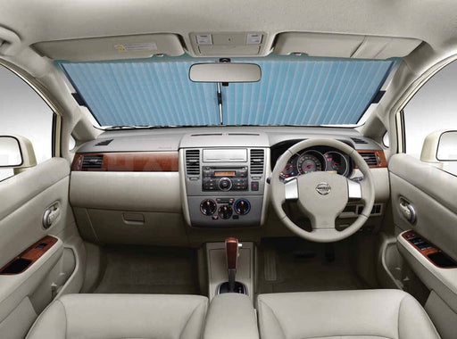 Interior of a beige car with a blue Mean Mother 4x4 Car Sun Shade 57cm Accordion covering the front windshield. The dashboard, steering wheel, and front seats are visible, illuminated by light from the windows.