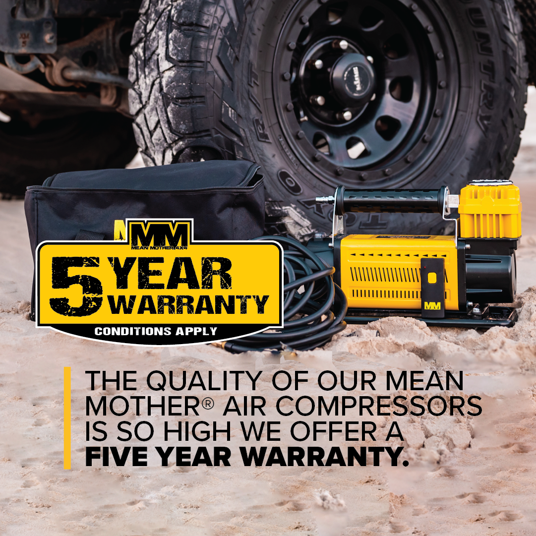 A Mean Mother Adventurer 4 â€“ 180lpm Air Compressor Bundle is displayed on the ground next to an off-road vehicle tire. A black bag with a prominent "5 Year Warranty" label showcases the product. Text below highlights the five-year warranty, underscoring the product's quality and robustness.